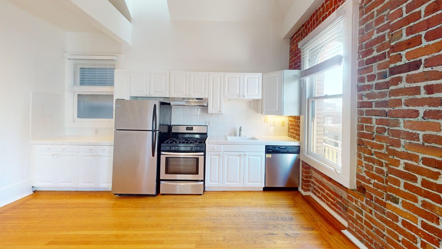 an empty kitchen with a brick wall and stainless steel appliances